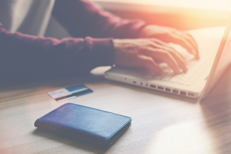 Man with laptop and credit card making online shopping, Intentional sun glare and lens flaresの写真素材