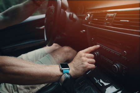 Man driving his car and tuning radio, smart watch on the handの写真素材