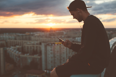 Risky man chilling on the edge of the roof at sunset, outdoorsの写真素材
