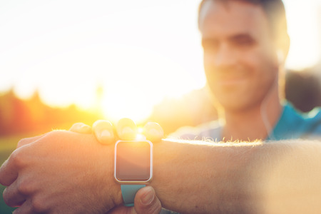 Close-up of smart watch on the wrist and smiling athlete on background, lens flares