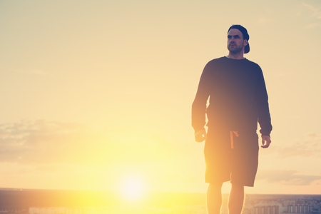 Brave risky man standing on the top of the roof at sunset, outdoorsの写真素材