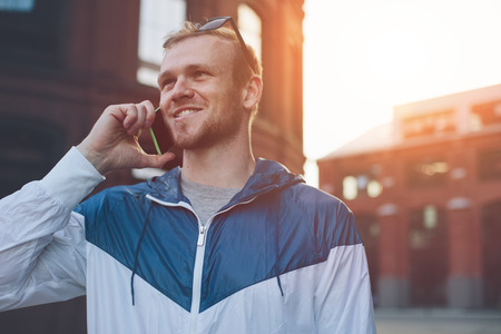 Smiling man speaking on the mobile phone on the street, outdoorsの写真素材