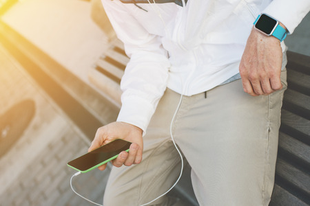 Man with mobile phone and smart watches sitting on the street, outdoorsの写真素材