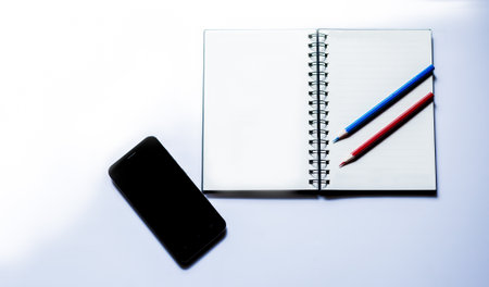Smartphone, notepad and pencil on dark background