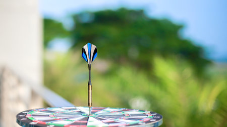 dart board has dart arrow throw hitting the center of a shooting target for business targeting and...