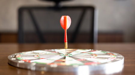 dart board has dart arrow throw hitting the center of a shooting target for business targeting and...