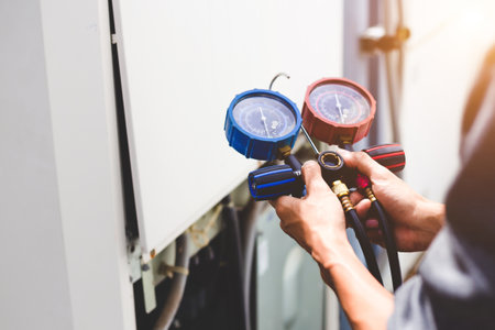 Air repair mechanic using measuring equipment for filling industrial factory air conditioners and...