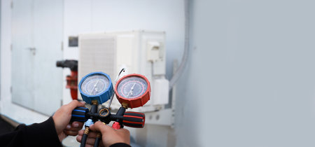 Air repair mechanic using measuring equipment for filling industrial factory air conditioners.の写真素材