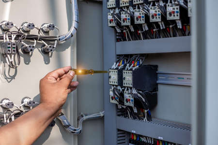 Electrical engineer tests the operation of the electric control cabinet on a regular basis for...