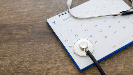 Stethoscope with date on calendar page on wooden table background doctor appointed health concept.の写真素材