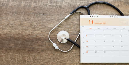 Stethoscope with date on a calendar page on a wooden floor. Healthcare concept.の写真素材