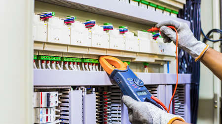 Electrical engineer tests the operation of the electric control cabinet on a regular basis for maintenance.のeditorial素材