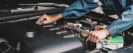 Car mechanic working on car engine, car maintenance concept.