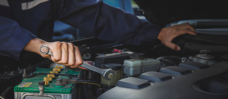 The mechanic works on the engine of the car in the garage, car repair service.の写真素材