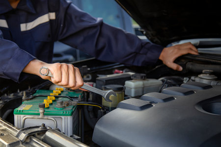 The mechanic works on the engine of the car in the garage, car repair service.の写真素材