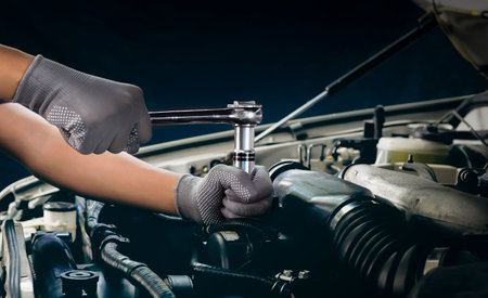 The mechanic works on the engine of the car in the garage, car repair service.の写真素材