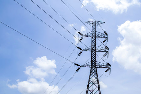 High voltage poles with sky and clouds in the background.の写真素材