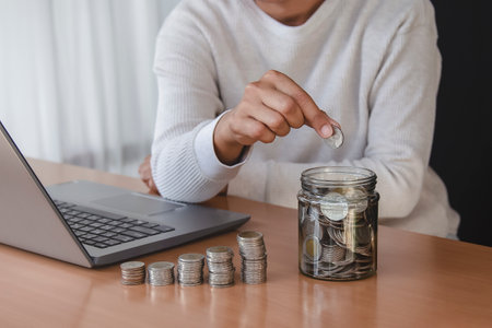 woman hand putting money coin into piggy for saving money wealth and financial concept.の写真素材
