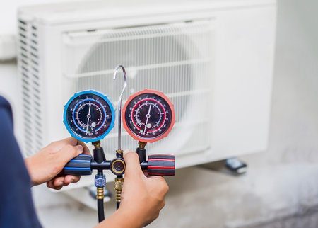 Air conditioning, HVAC service technician using gauges to check refrigerant and add refrigerant.の写真素材