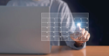Businessman using pen to set meeting agenda on calendar as appointment planning conceptの写真素材
