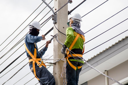 Electricians working on power pole connecting cablesの写真素材