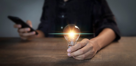 businessman holding an innovative light bulb creating new ideas inspirational ideas and problem...