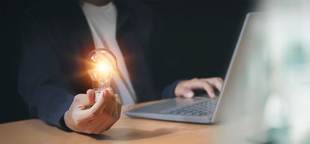 businessman holding an innovative light bulb creating new ideas inspirational ideas and problem solvingの写真素材