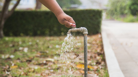 Man's hand pouring water from tap in the garden, stock photoの写真素材