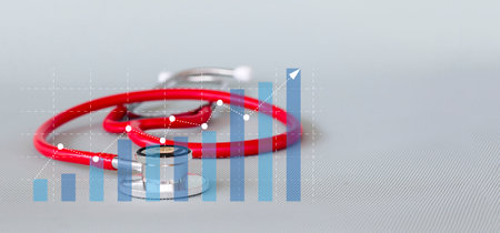 Stethoscope and red graph on gray background. Medical and healthcare concept.