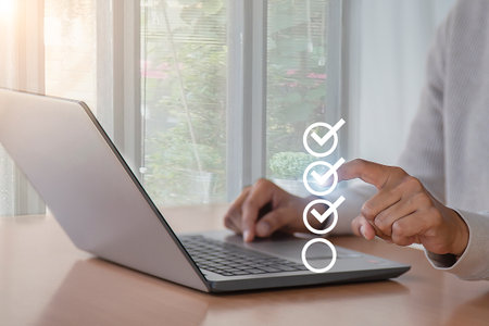 Businessman hand using laptop computer with check mark icon on screen.