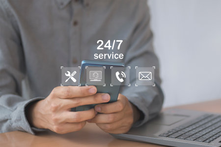 Businessman using mobile phone with 24/7 service icon on screenの写真素材