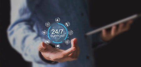 Businessman on blurred background using 24/7 service interface with his handの写真素材