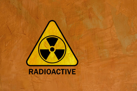 Radioactive sign written on a concrete wall, warning of occupational safety, on a yellow background.の写真素材