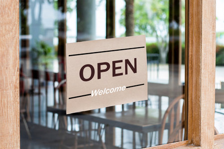 A sign that says "Open" in a coffee shop or restaurant is hung at the entrance door.の写真素材