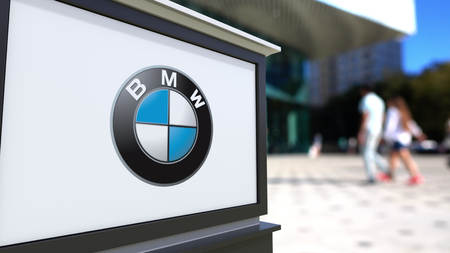 Street signage board with BMW logo. Blurred office center and walking people background. Editorial 3D rendering United Statesのeditorial素材