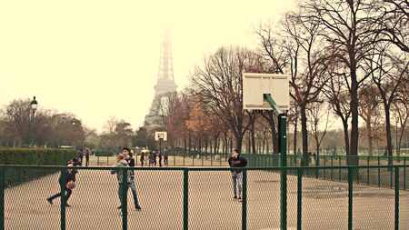 PARIS, FRANCE - DECEMBER, 31, 2016. Multinatonal male teenagers playing street basketball against Eiffel Tower on a foggy day, warm colorsのeditorial素材