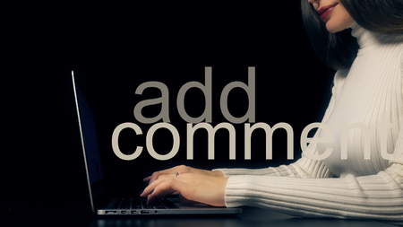 Beautiful brunette woman typing on her laptop against black background. Add comment inscriptionの写真素材