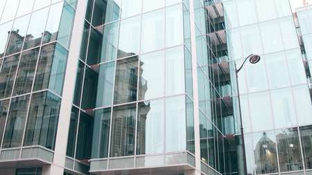 Distorted reflection of old building in modern office glass facade in Paris. Opposites concept