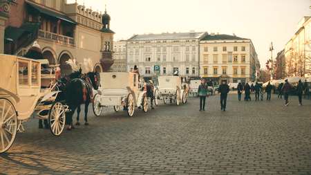 KRAKOW, POLAND - JANUARY, 14, 2017 Retro horse drawn carriages and Old town street, warm colorsのeditorial素材