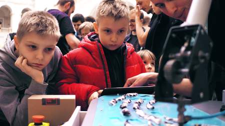 WARSAW, POLAND - MARCH, 4, 2017. Engineer demonstrates robotic arm operation to little boysのeditorial素材