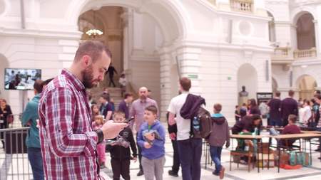WARSAW, POLAND - MARCH, 4, 2017. Young bearded man in plaid shirt using his smartphone in public...