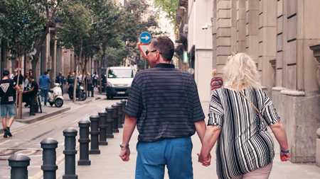 BARCELONA, SPAIN - APRIL, 15, 2017. Mature couple walking holding hands along the street