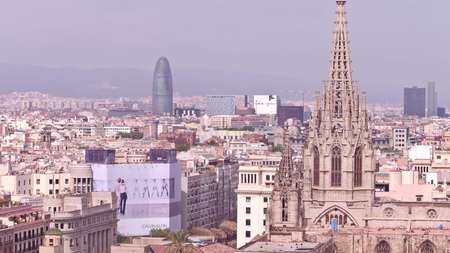 BARCELONA, SPAIN - APRIL, 15, 2017. Church spire and distant Torre Agbarのeditorial素材