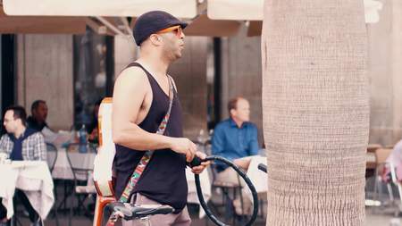 BARCELONA, SPAIN - APRIL, 15, 2017. Fashionable young man with guitar locking his bicycle in the...
