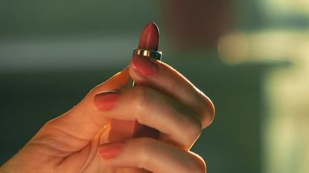 Young woman opens red lipstickの写真素材