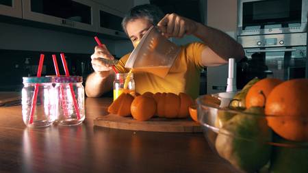 Handsome man making fresh orange juice at homeの写真素材