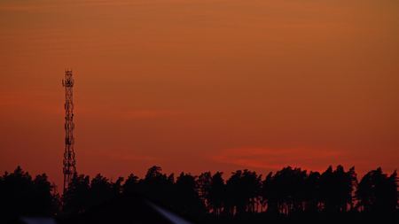 Silhouette of a cellular tower or cell site against orange evening sky