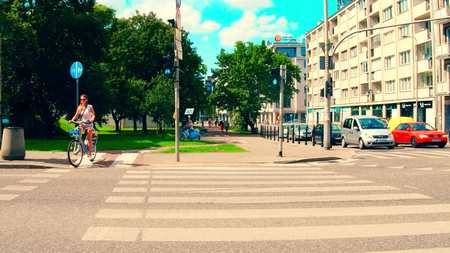 WARSAW, POLAND - JULY 11, 2017. Young woman cycling along the city crosswalk