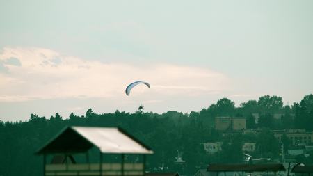 Unknown powered paraglider flying near the townの写真素材