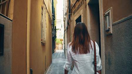 VENICE, ITALY - AUGUST 8, 2017. Young woman walking along narrow pedestrian street near Burberry fashion storeのeditorial素材